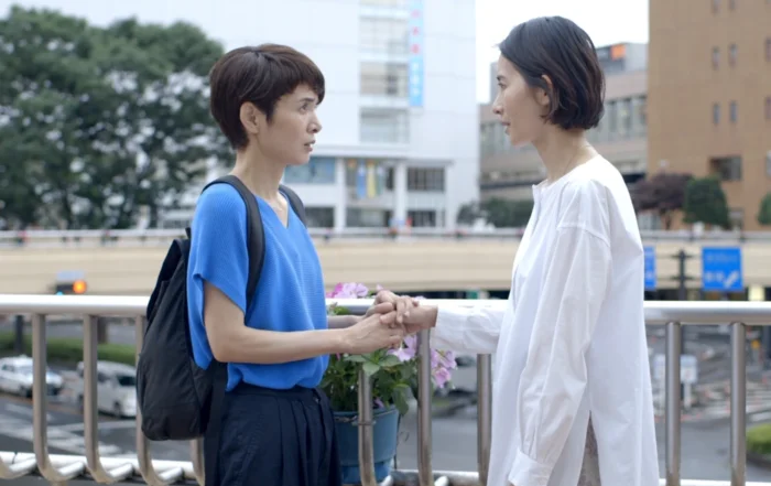 Das Glücksrad Filmstill, zwei Personen stehen sich gegenüber und unterhalten sich auf einer Brücke