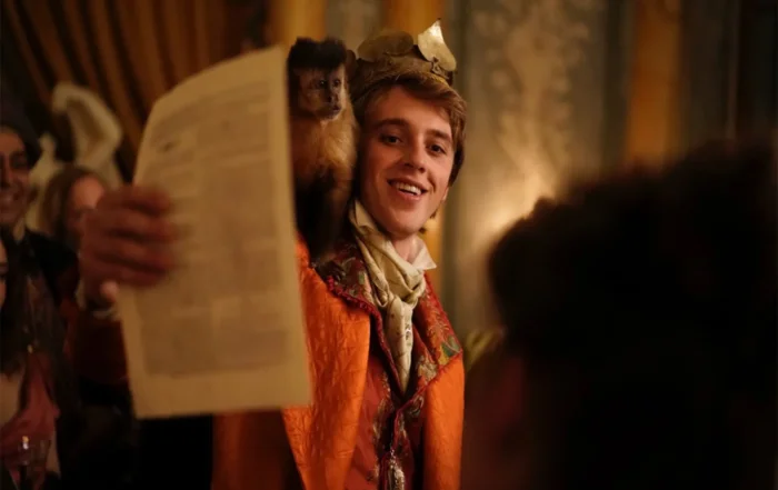 Szenenbild: junger weißer Mann im 19. Jahrhundert hält Zeitungsseite