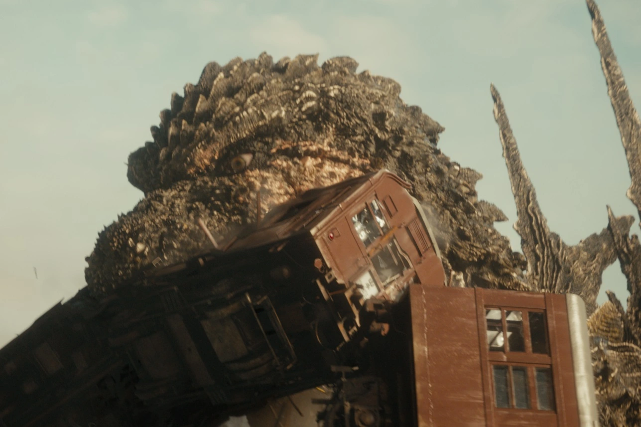 Godzilla in einer Nahaufnahme, ein Lastwagen klemmt zwischen den Zähnen