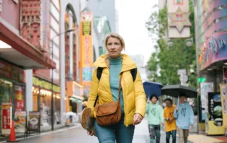 eine Frau im gelben Anorak spaziert durch die Innenstadt
