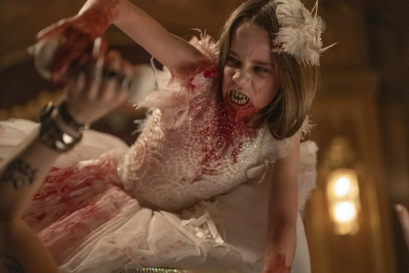ein Mädchen in einem weißen, blutbefleckten Kleid baut sich vor seinem Opfer auf und fletscht die Zähne