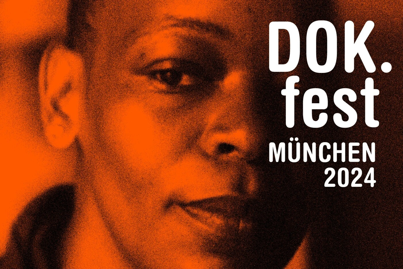 Plakatmotiv des DOK.fest München 2024, Großaufnahme eines Jungengesichts, das von orangefarbenen Licht angestrahlt wird, rechts im Bild steht in weißer Schrift: DOK.fest München 2024