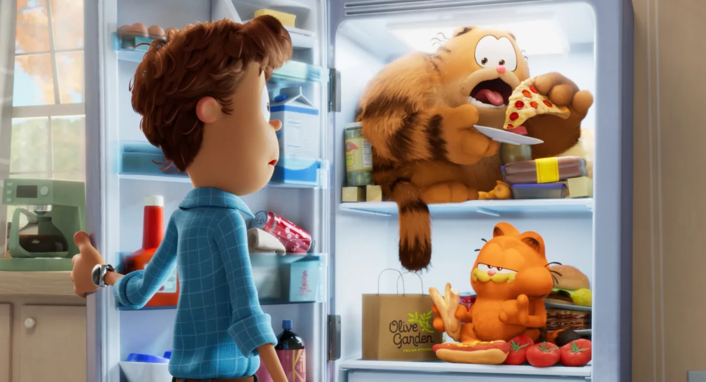 Jon steht vor seinem geöffneten Kühlschrank, im Kühlschrank sitzen zwei orange-schwarz gestreifte, schlemmende Katzen, Garfield in der mittleren Etage, sein Vater in der oberen Etage