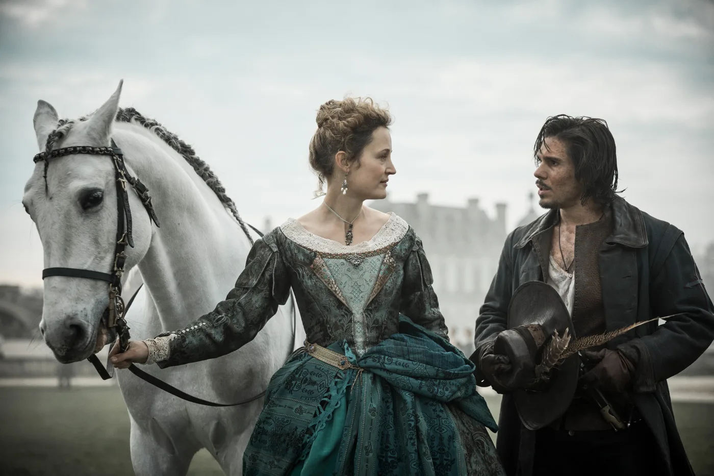 im Hintergrund erhebt sich eine Burg in der Ferne, im Vordergrund steht ein weißes Pferd, dessen Zügel von einer danebenstehenden Frau im dunkelgrünen Kleid gehalten werden, die Frau spricht mit einem bewaffneten Mann