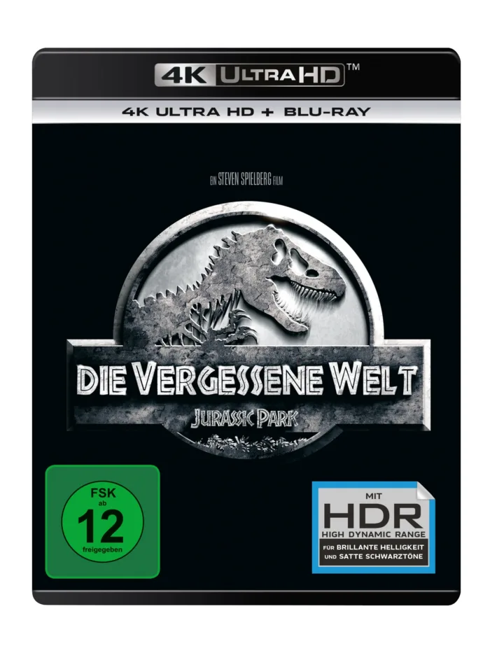 4K Ultra-HD und Blu-Ray Cover des Films, schwarzer Hintergrund mit einem silbernen Siegel auf dem die Umrisse eines Sauriers und die Aufschrift: "DIE VERGESSENE WELT - JURASSIC PARK" zu sehen ist, links auf dem Cover befindet sich das grün-leuchtende FSK-12-Symbol