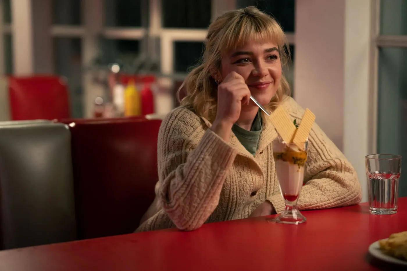 Almut (Florence Pugh) sitzt in einem Cafe vor einem Eisbecher, aus dem zwei Waffeln rageln