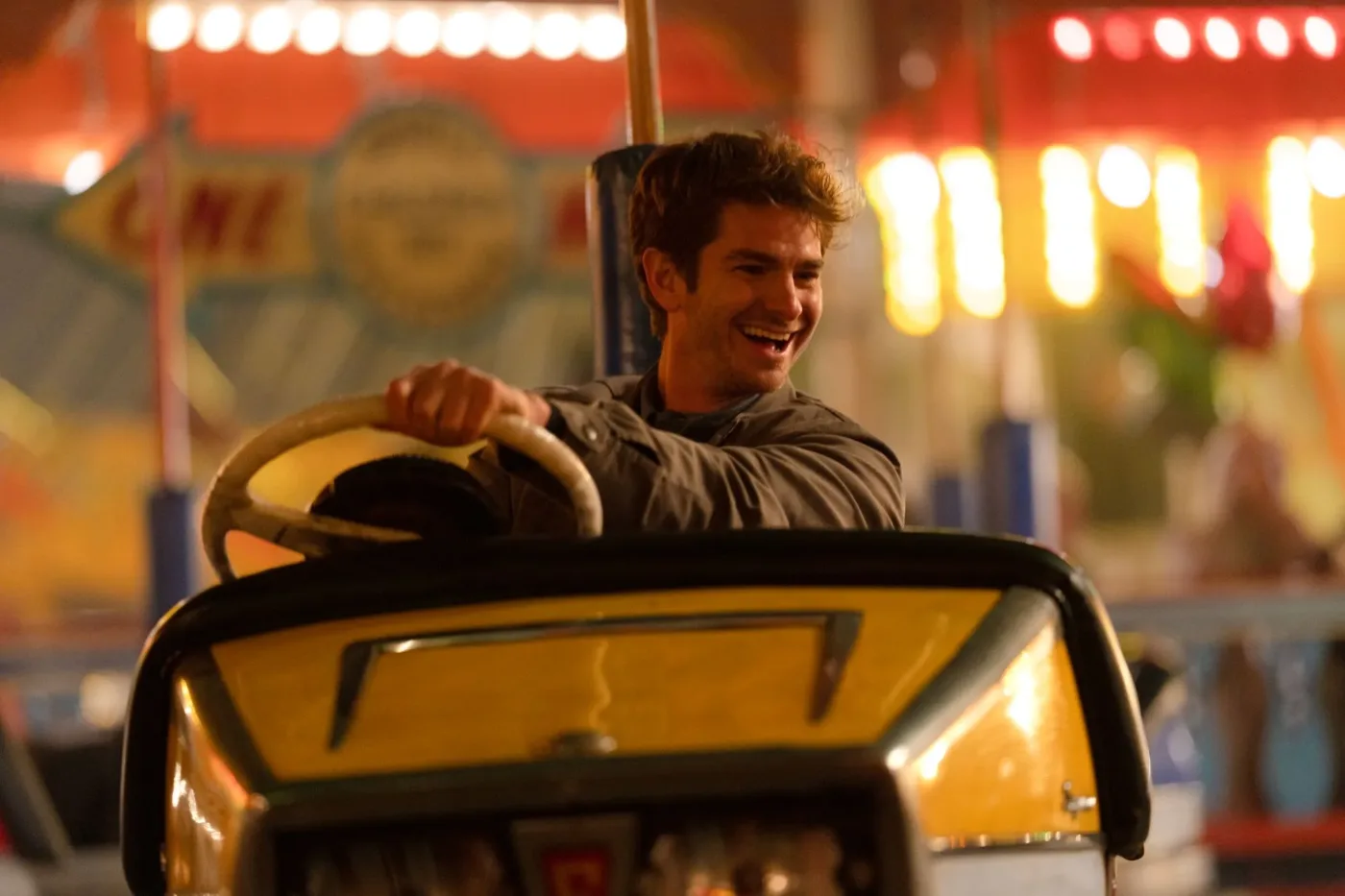 in einem Autoscooter sitzt Tobias (Andrew Garfield) am Lenkrad eines gelben Wagens