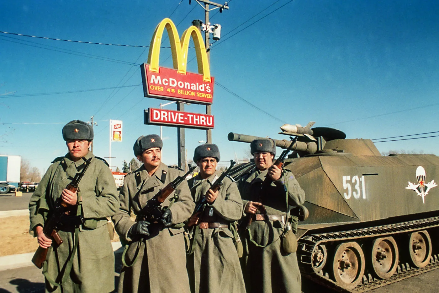 vier Soldaten mit Gewehren bewaffnet stehen vor einem McDonald-Schild