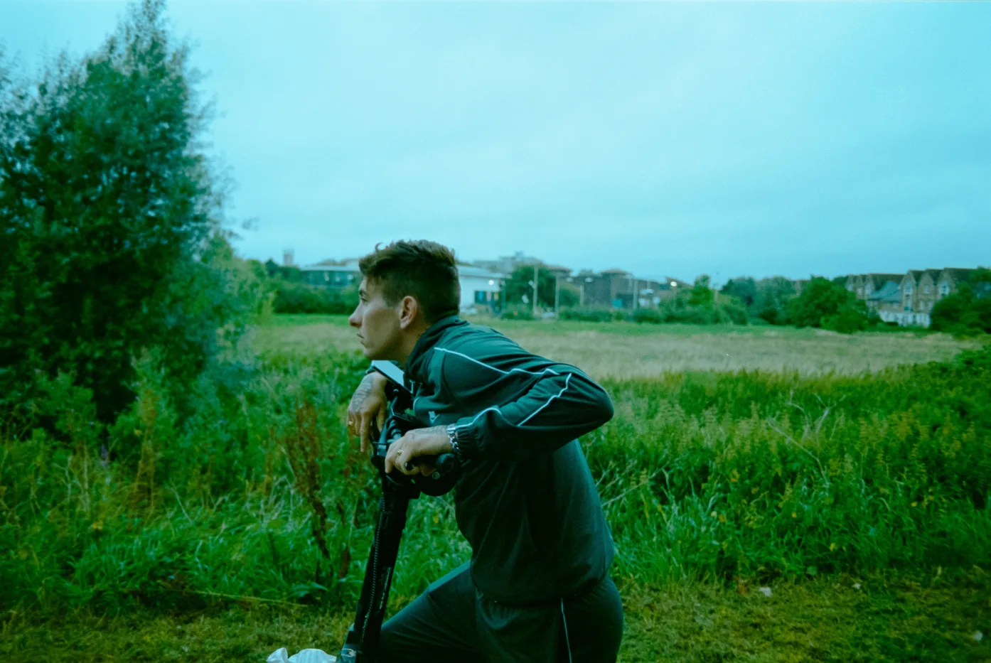 Bug (Barry Keoghan) lehnt auf einem Roller vor einer Graslandschaft