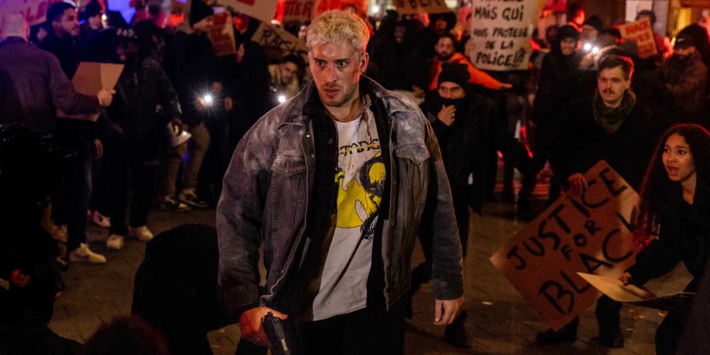 vor in schwarzgekleideten Demonstranten steht ein blonder Mann
