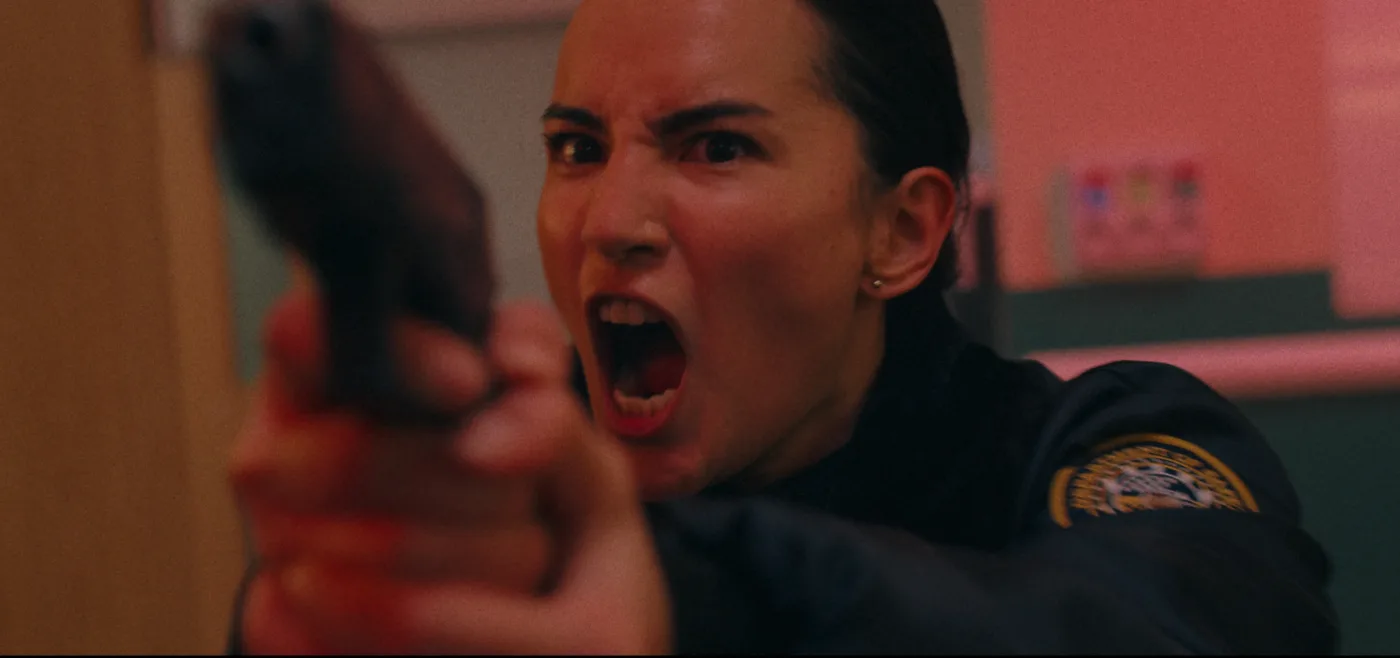 Jessi Mei Li als Polizistin mit gezogener Waffe