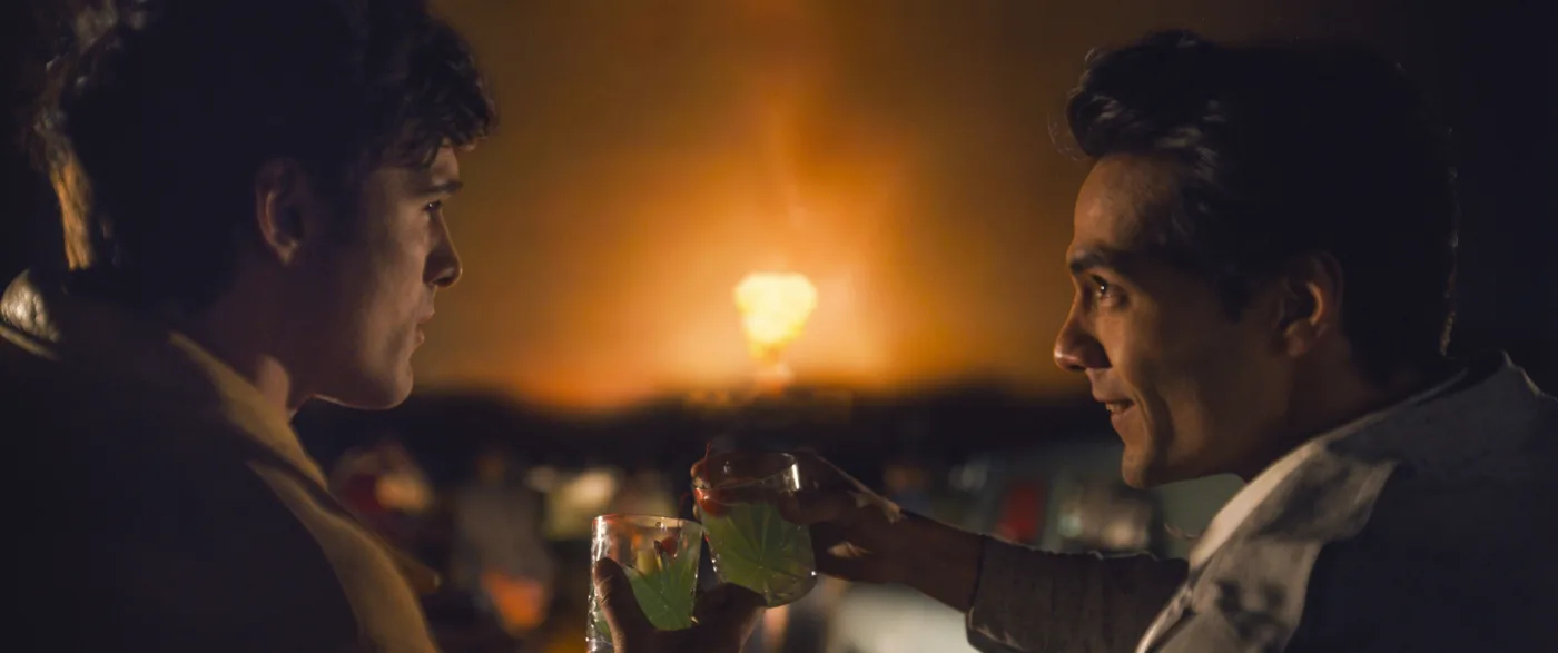 Nahaufnahme zweier junger Männer, die mit einem Glas anstoßen und sich dabei in die Augen sehen