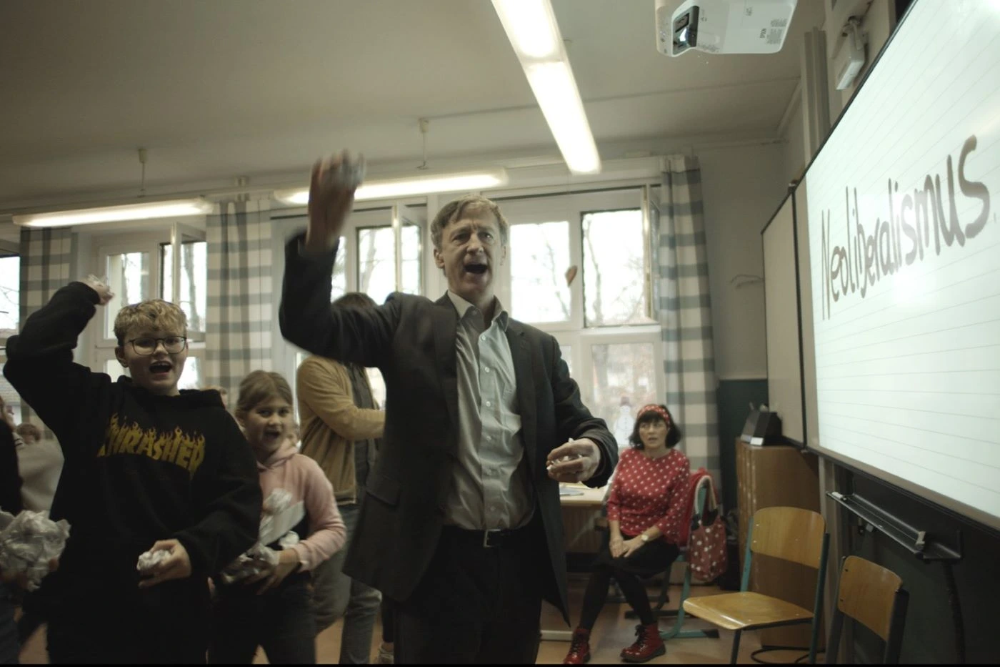 Jan Henrik Stahlberg als Mux vor einer Schulklasse mit geballter Faust skandierend