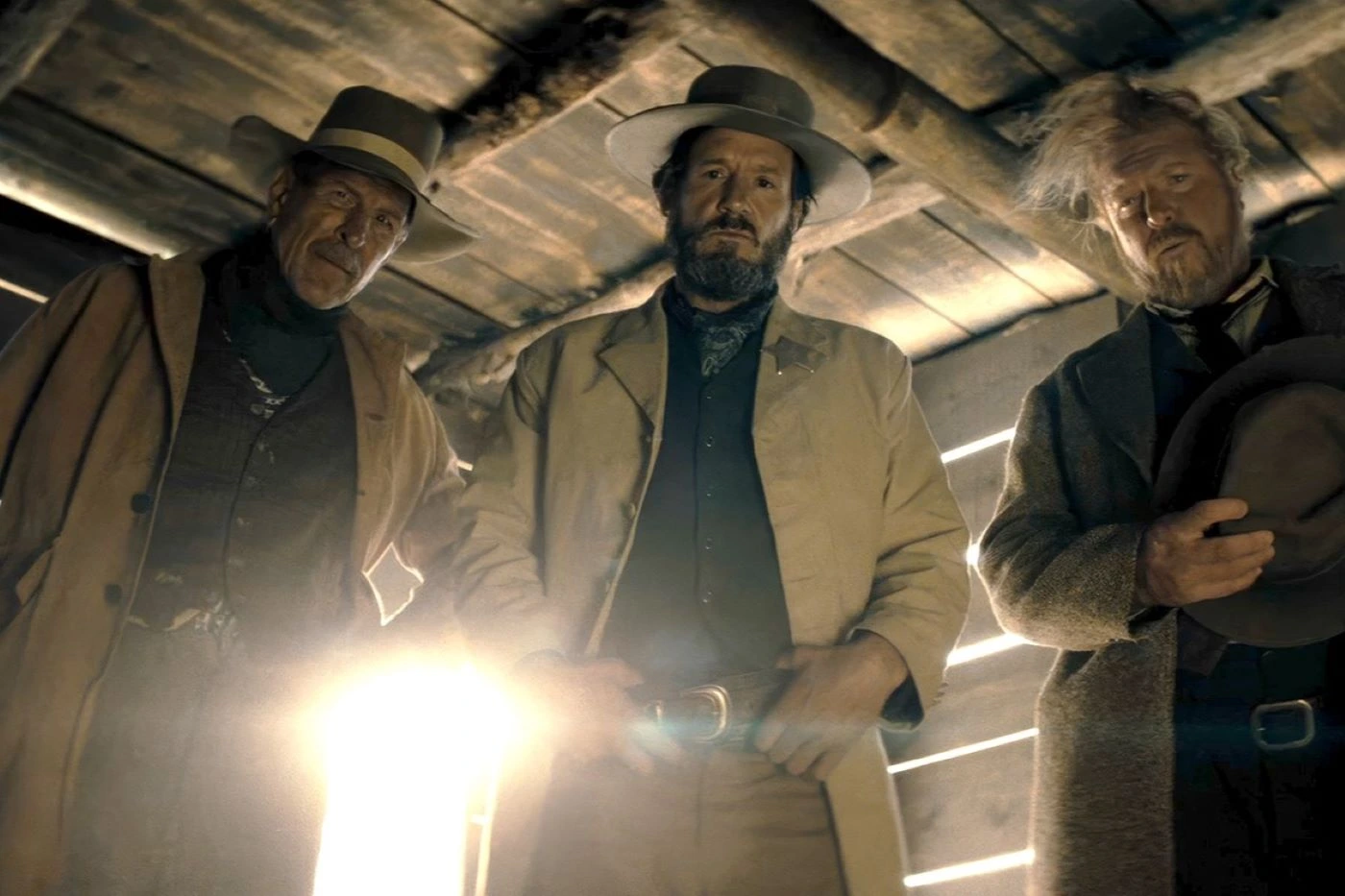 Henry Tibbs (Tyler Gaisford), Wood Helm (Josh Hopkins) und Drum (Jake Busey) als Cowboys in einer Scheune, sie schauen von oben auf die Kamera herab