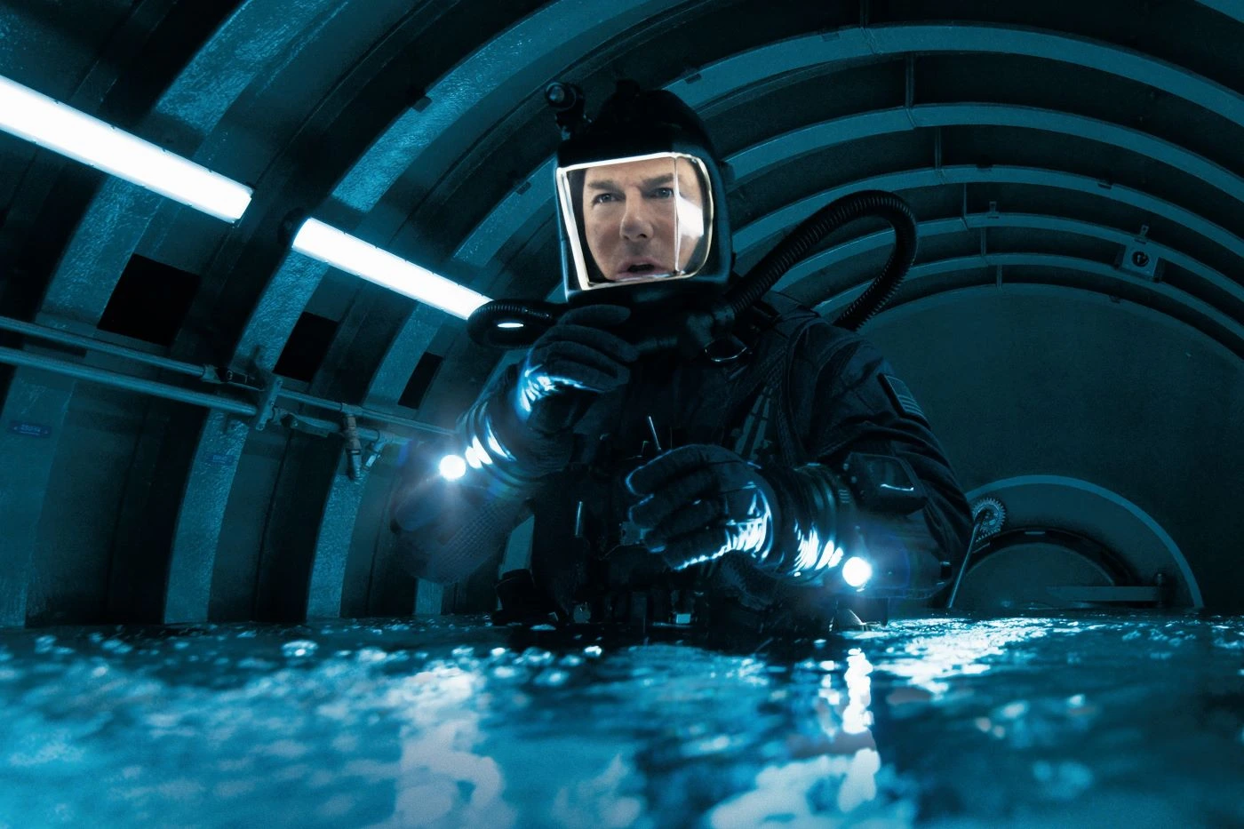 Tom Cruise als Ethan Hunt in einem schwarzen Taucheranzug in einem Gang, der sich mit Wasser füllt