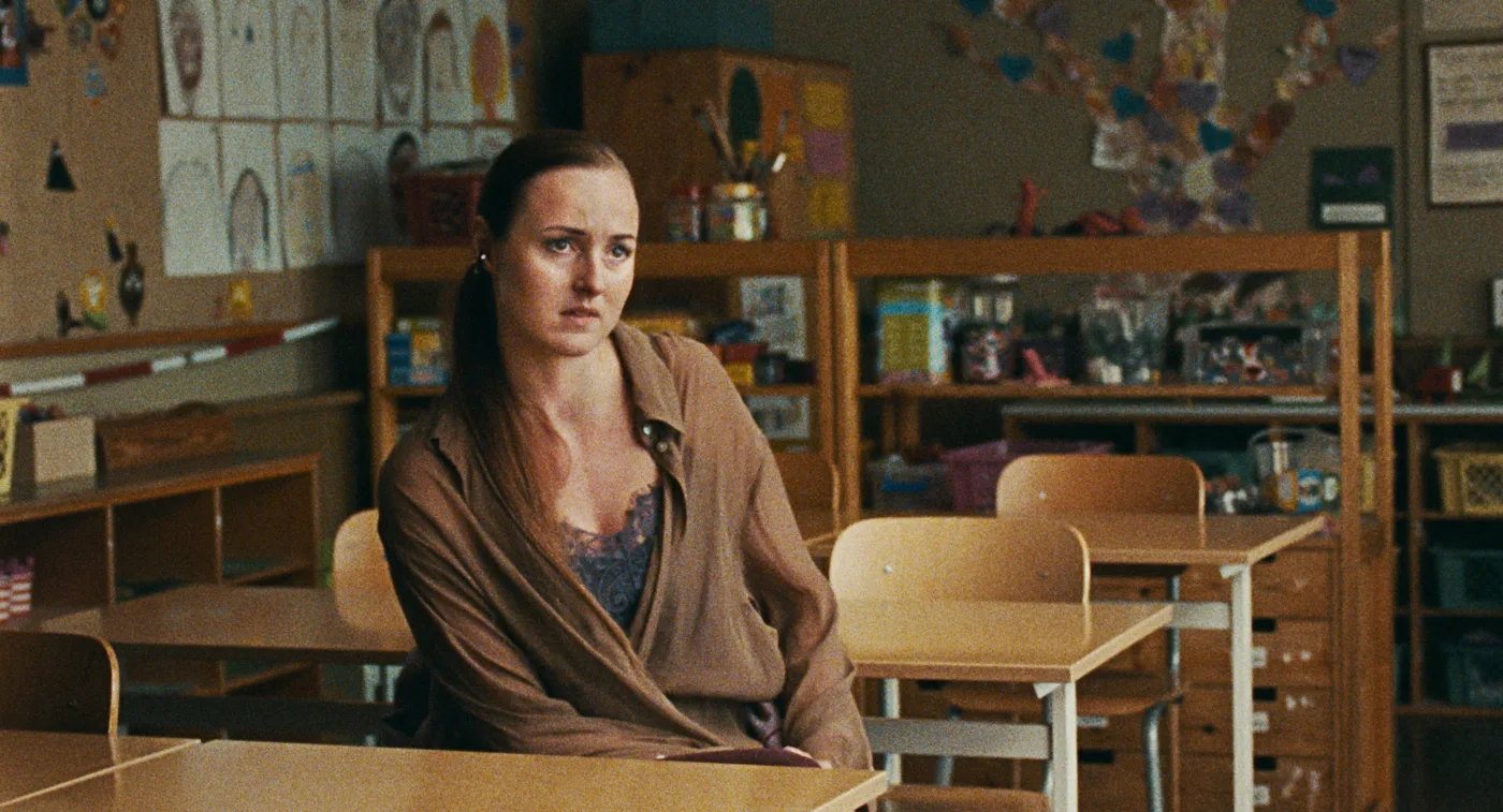in einem leeren Klassenzimmer sitzt eine Frau in der ersten Reihe