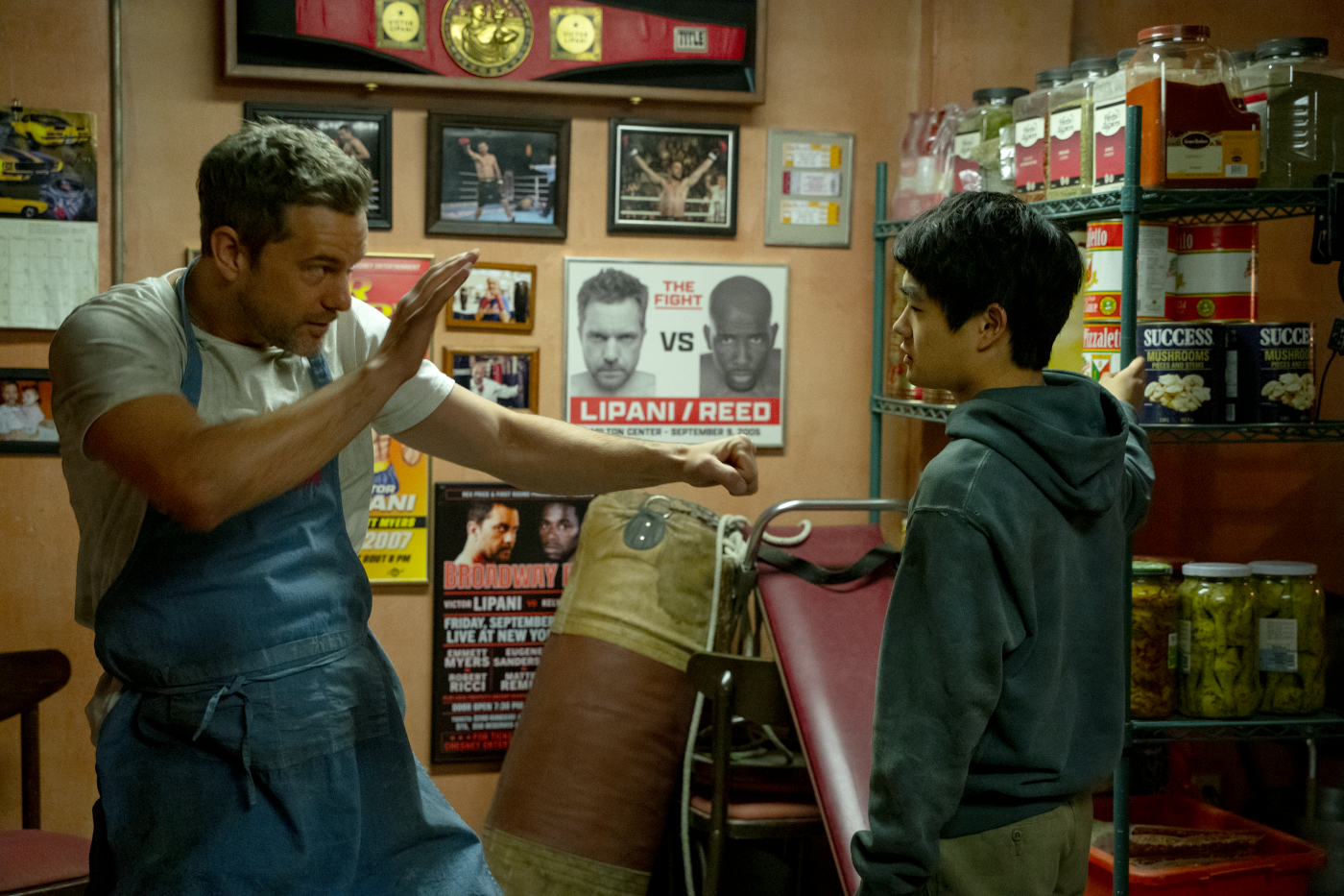 Joshua Jackson and Ben Wang vor einer Wand mit Bildern von Boxern in Columbia Pictures KARATEKID: LEGENDS