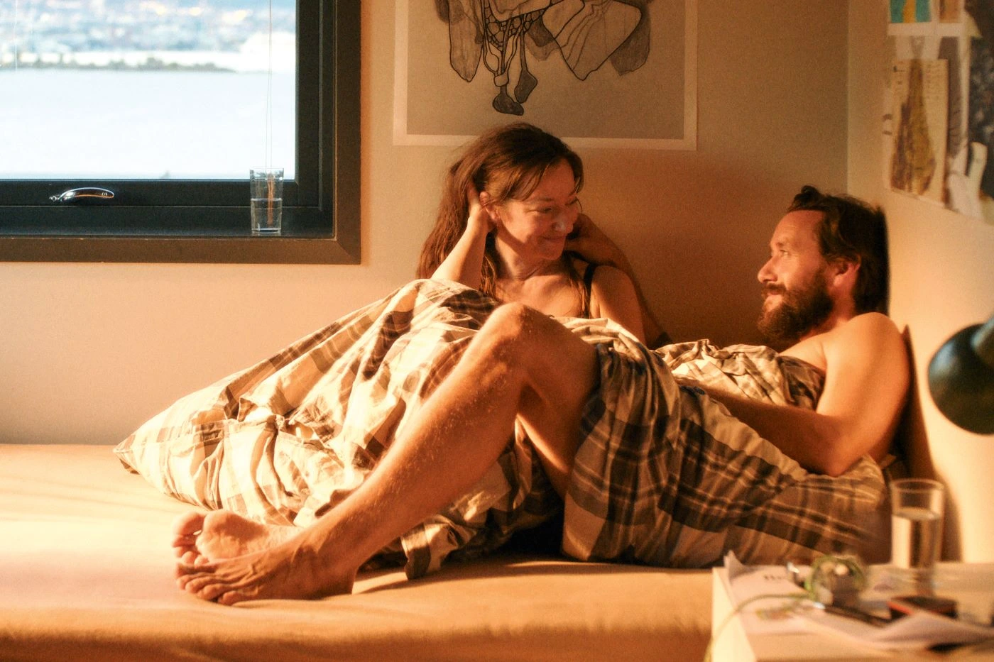 ein Mann und eine Frau liegen gemeinsam in einem Einzelbett an der Wand eines Zimmers
