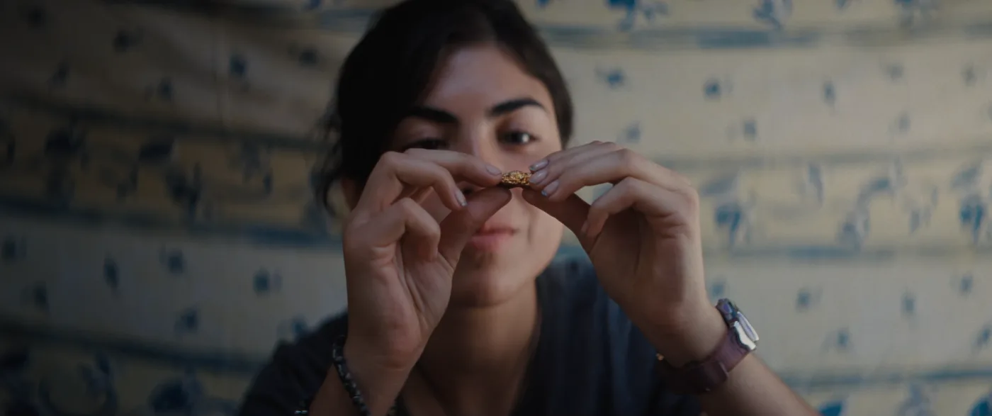 Carola hält ein kleines Stück Gold zwischen ihren Fingern