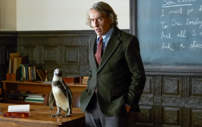 Steve Coogan als Lehrer Tom vor der Tafel eines Klassenzimmers, recht neben ihm steht ein Pinguin auf dem Lehrerpult