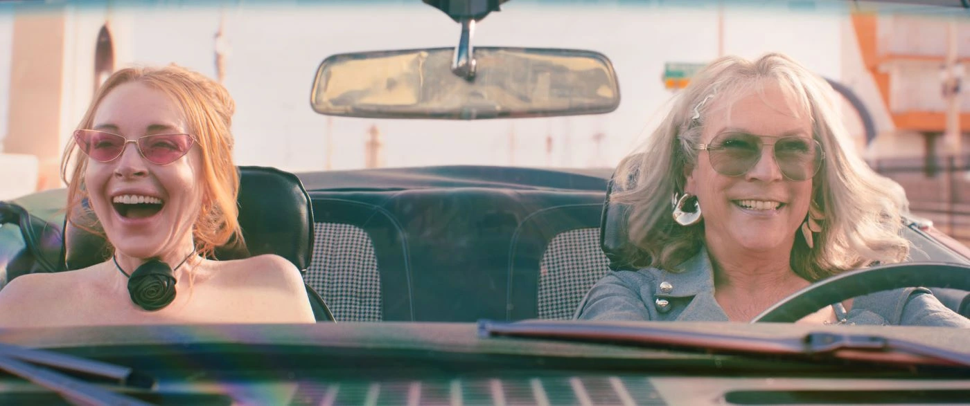 zwei Frauen im Auto, eine Fahrerin und eine Beifahrerin, lachend, mit offenem Dach