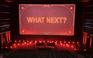 Blick in einen Kinosaal mit großer Leinwand und der Aufschrift „What Next?“ während der Netflix-Programmvorstellung in Berlin.