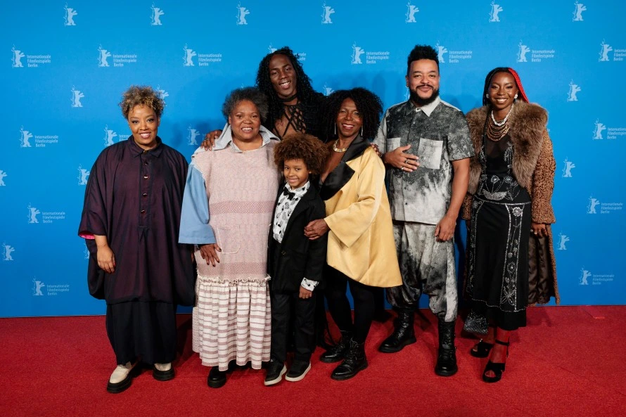 Vor blauem Hintergrund mit kleinen weißen Bären posieren Cast und Crew des Films Our Secret.