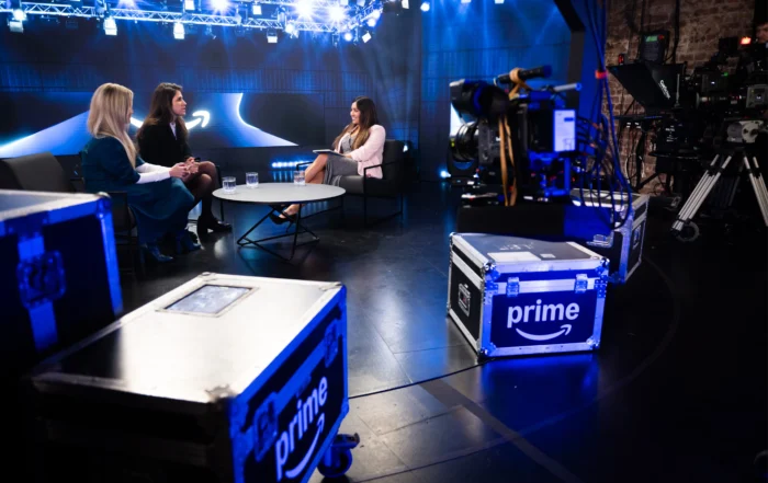 Prime-Video-Programmpräsentation in modernem Studio: Drei Gesprächspartnerinnen sitzen bei einer aufgezeichneten Diskussionsrunde unter Studiolicht, im Vordergrund Kameratechnik und Transportkisten mit Prime-Logo.